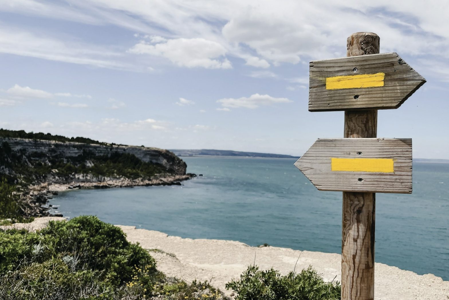 A wooden signpost pointing in two directions by the sea