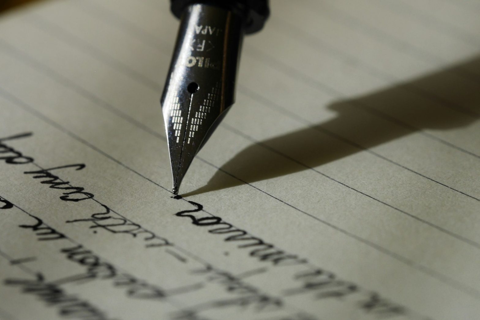 A fountain pen writing on lined paper